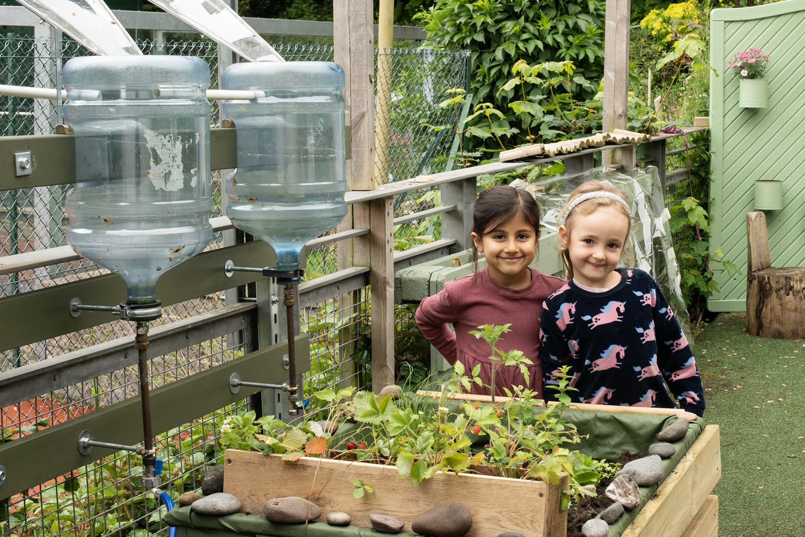Children beside the upcycled water collectors in the Pocket Picnic Garden