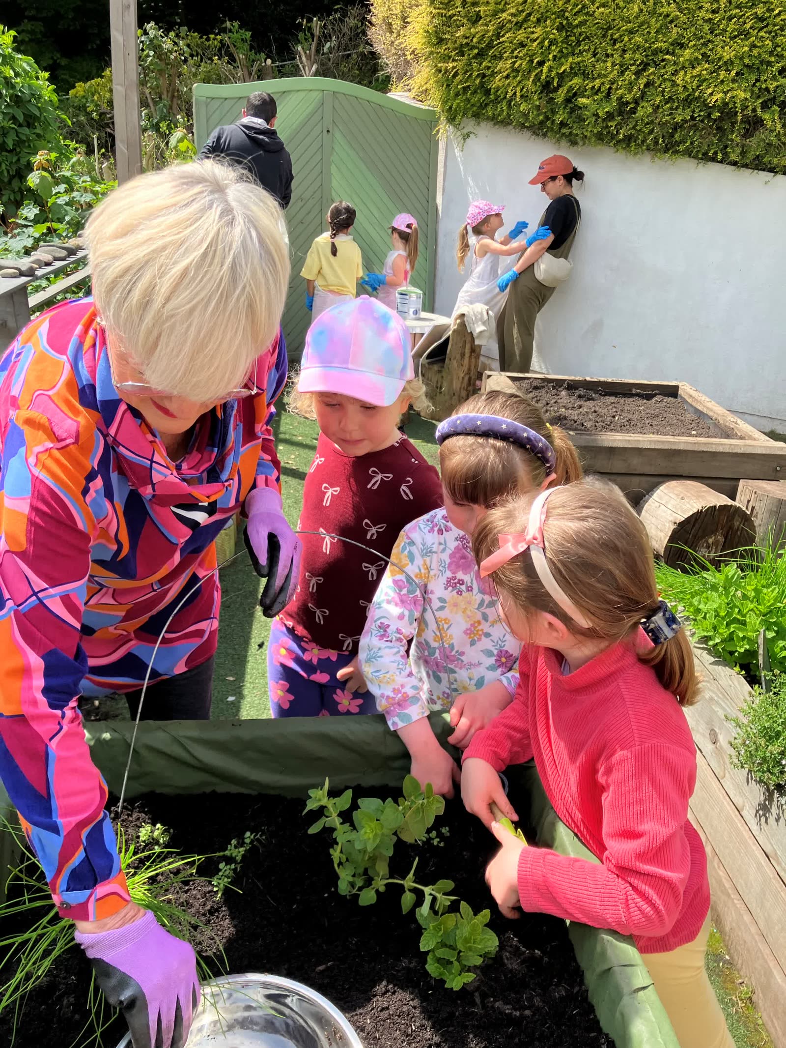 A staff member and children looking at the Pocket Picnic Garden together