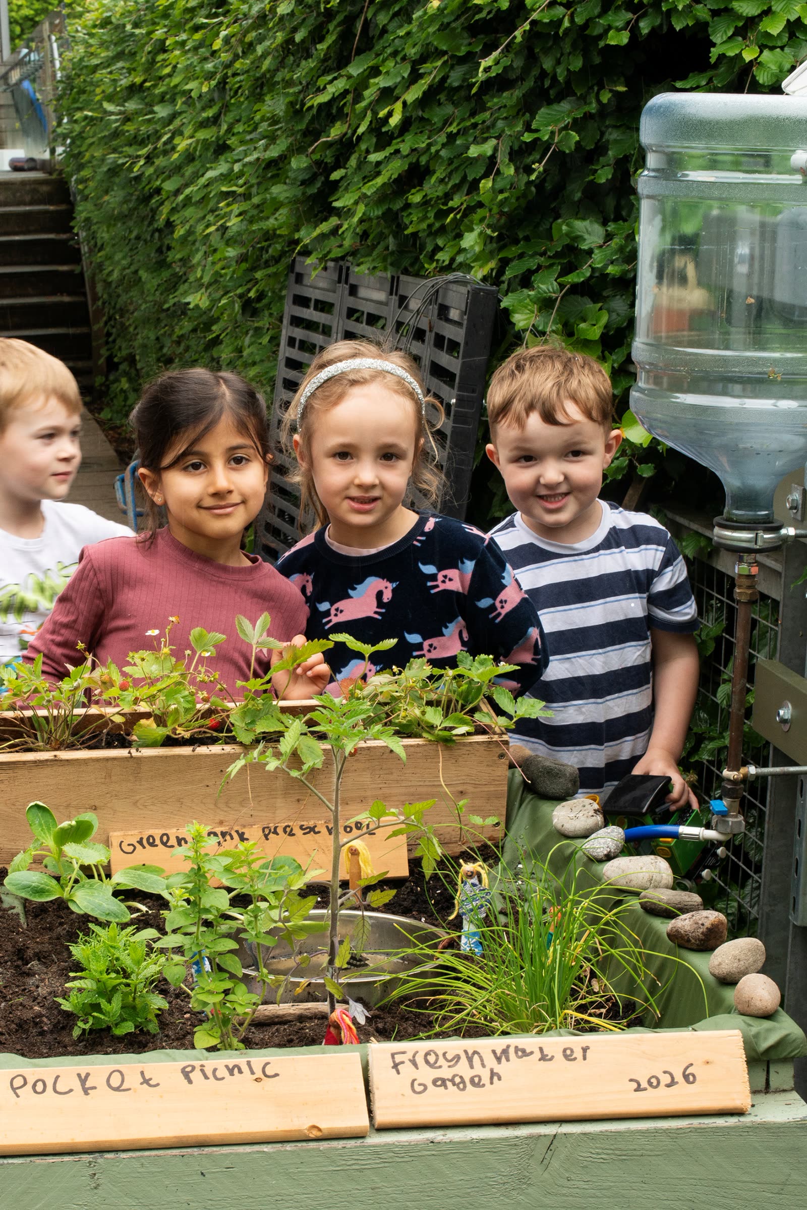 Three children beside the Pocket Picnic Freshwater Garden 2026 sign