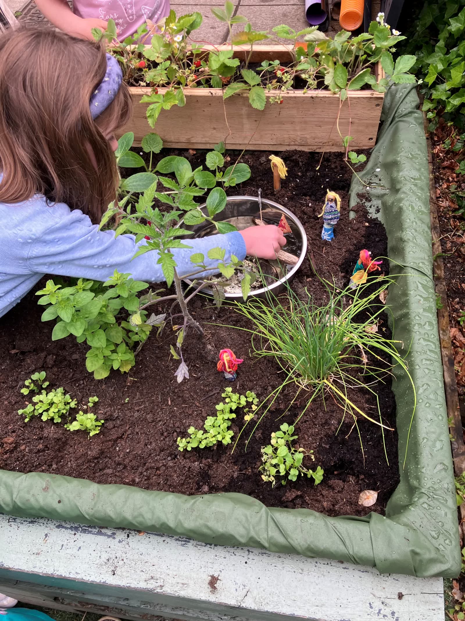 A child planting with small figures placed around the Pocket Picnic Garden