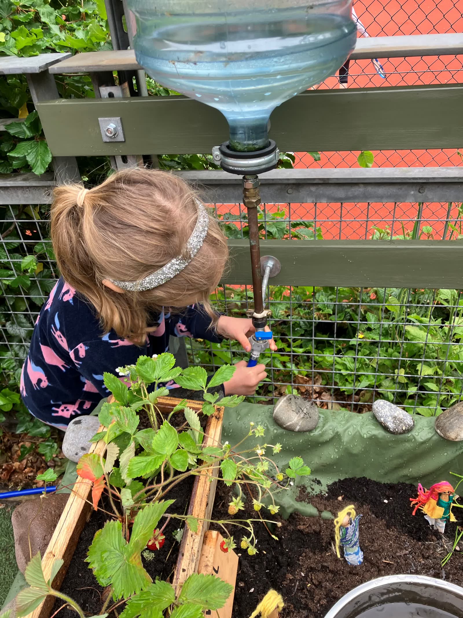 A child using one of the upcycled water collectors in the Pocket Picnic Garden