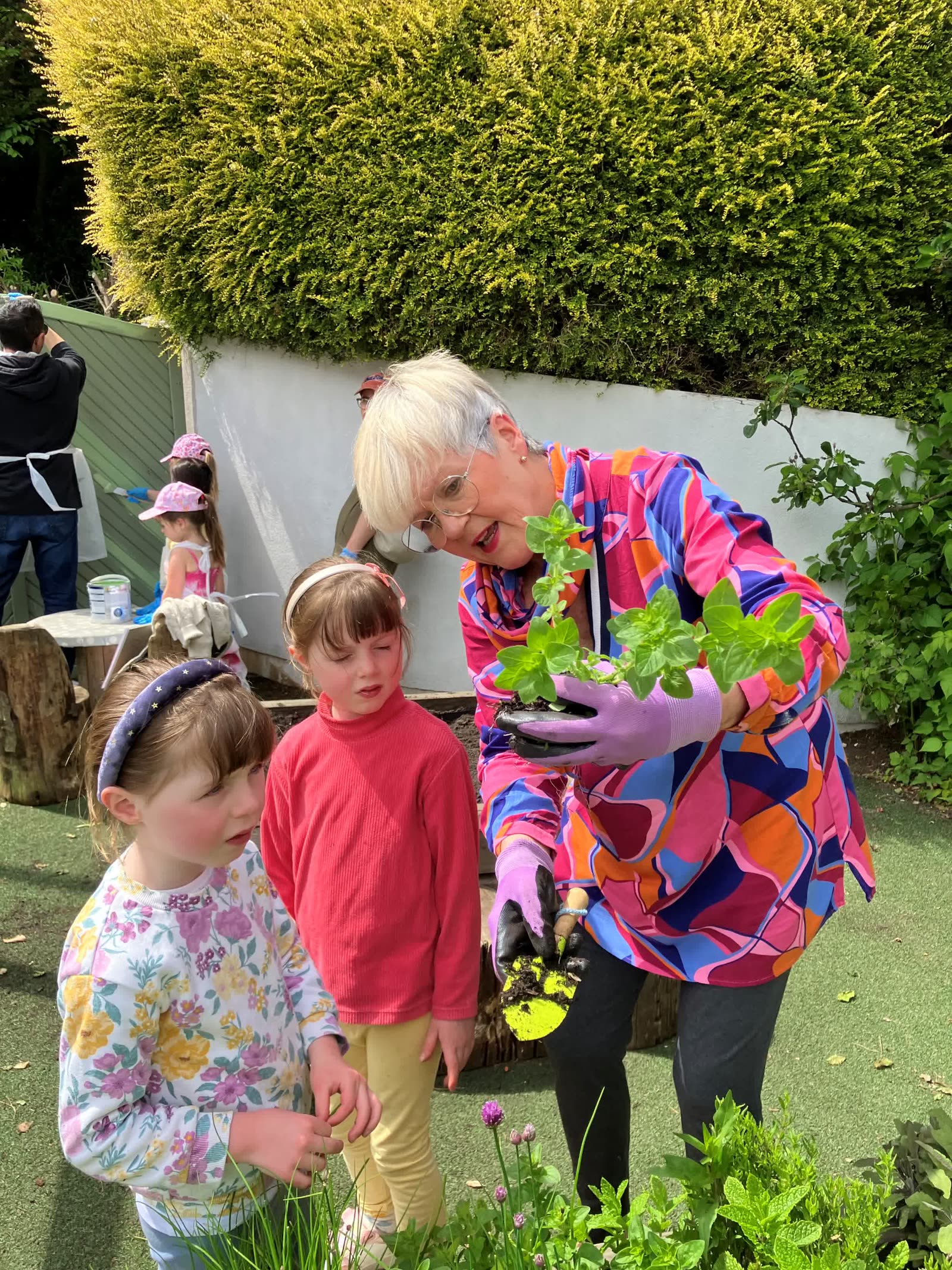 A staff member and children planting herbs in the Pocket Picnic Garden