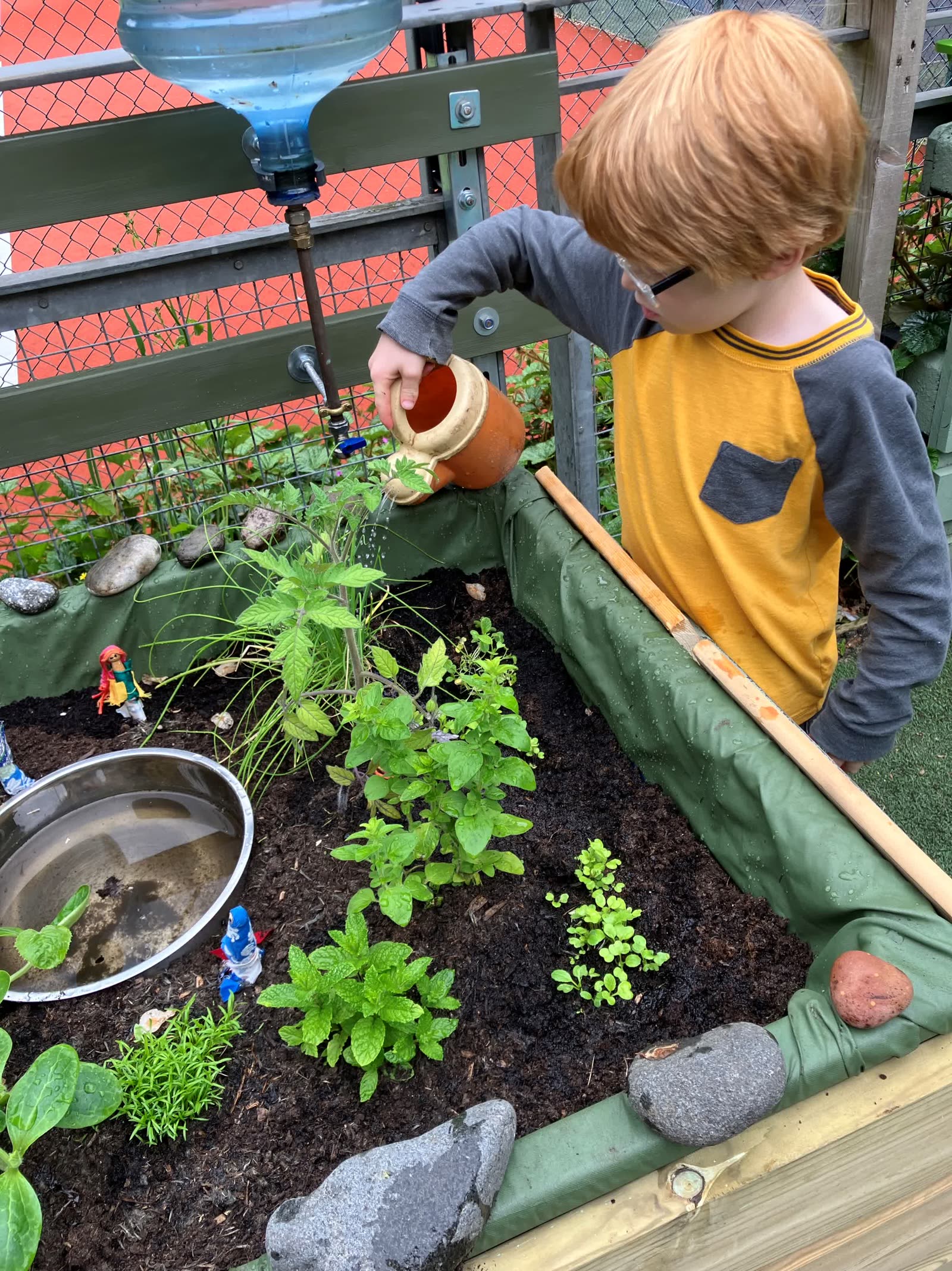 A child watering the Pocket Picnic Garden using the upcycled water collectors